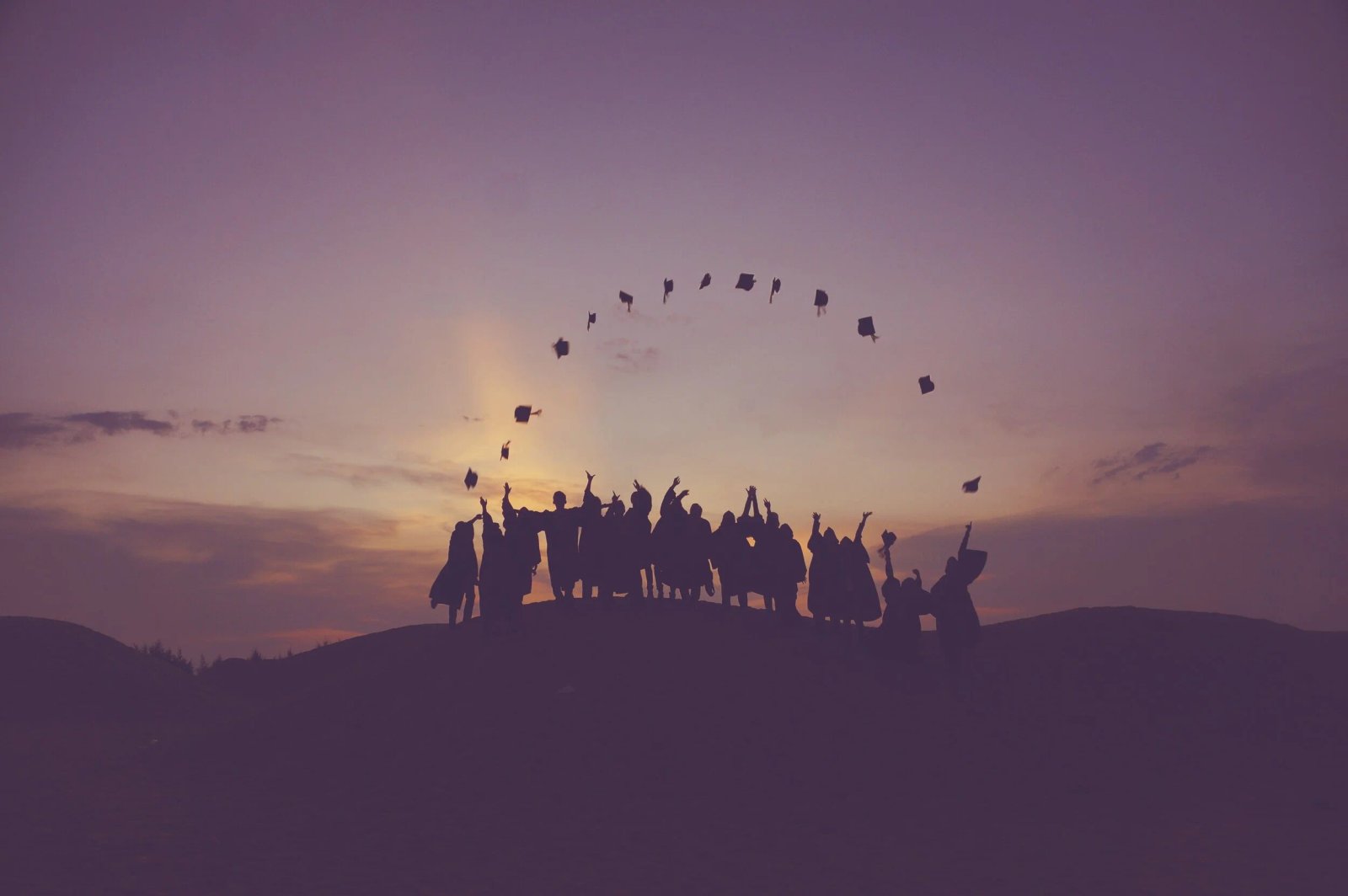 Empowerment Through Unity — graduates celebrating at sunset